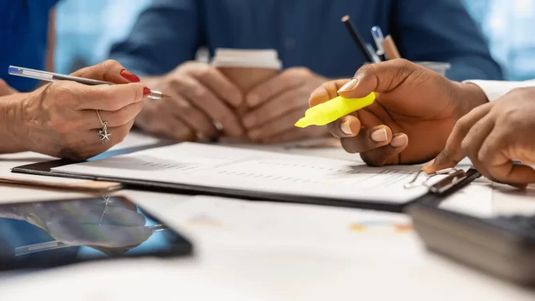 Two advisors reviewing and annotating financial planning documents at a meeting