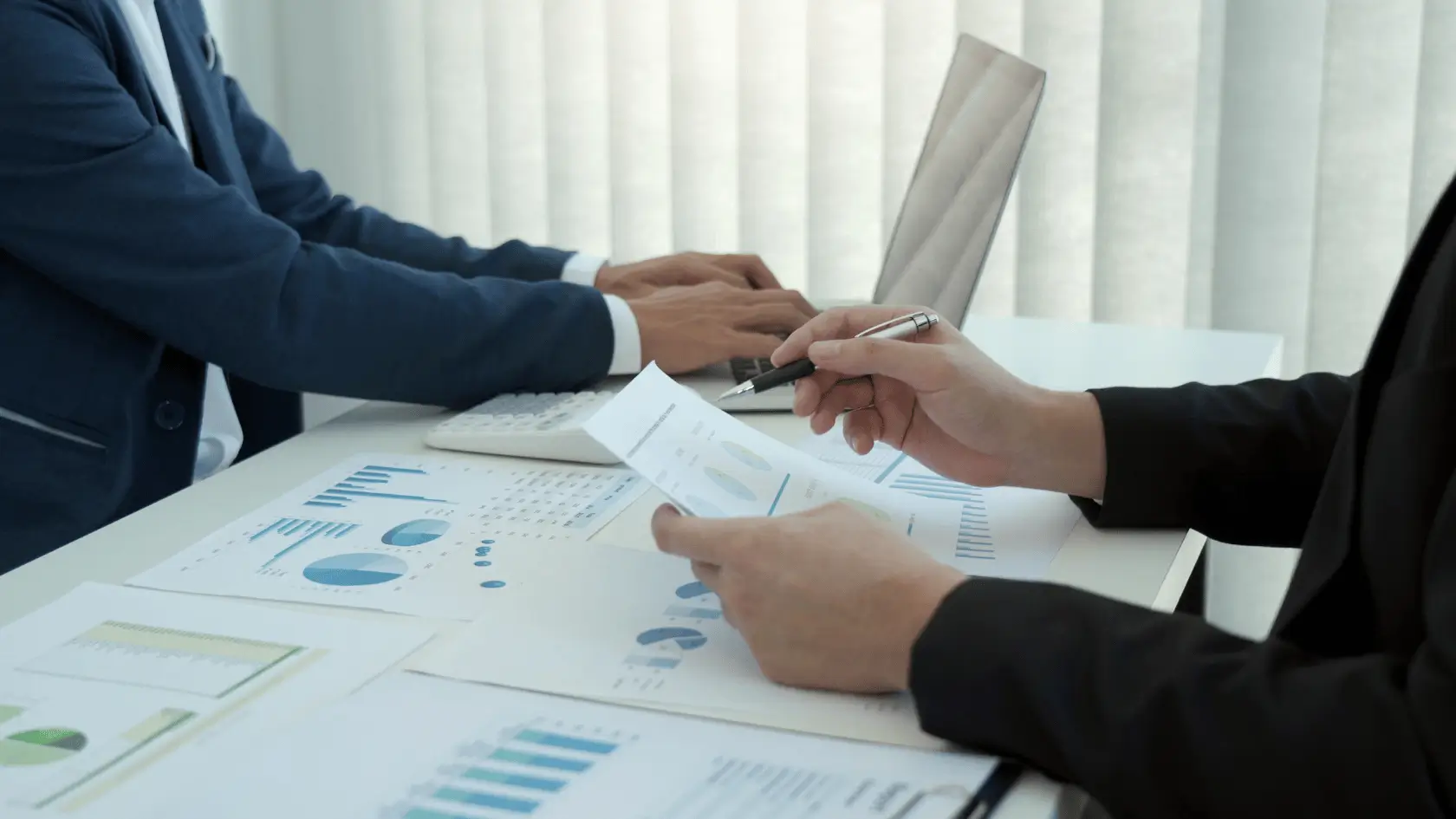 Two professionals reviewing a coordinated financial blueprint at a conference table