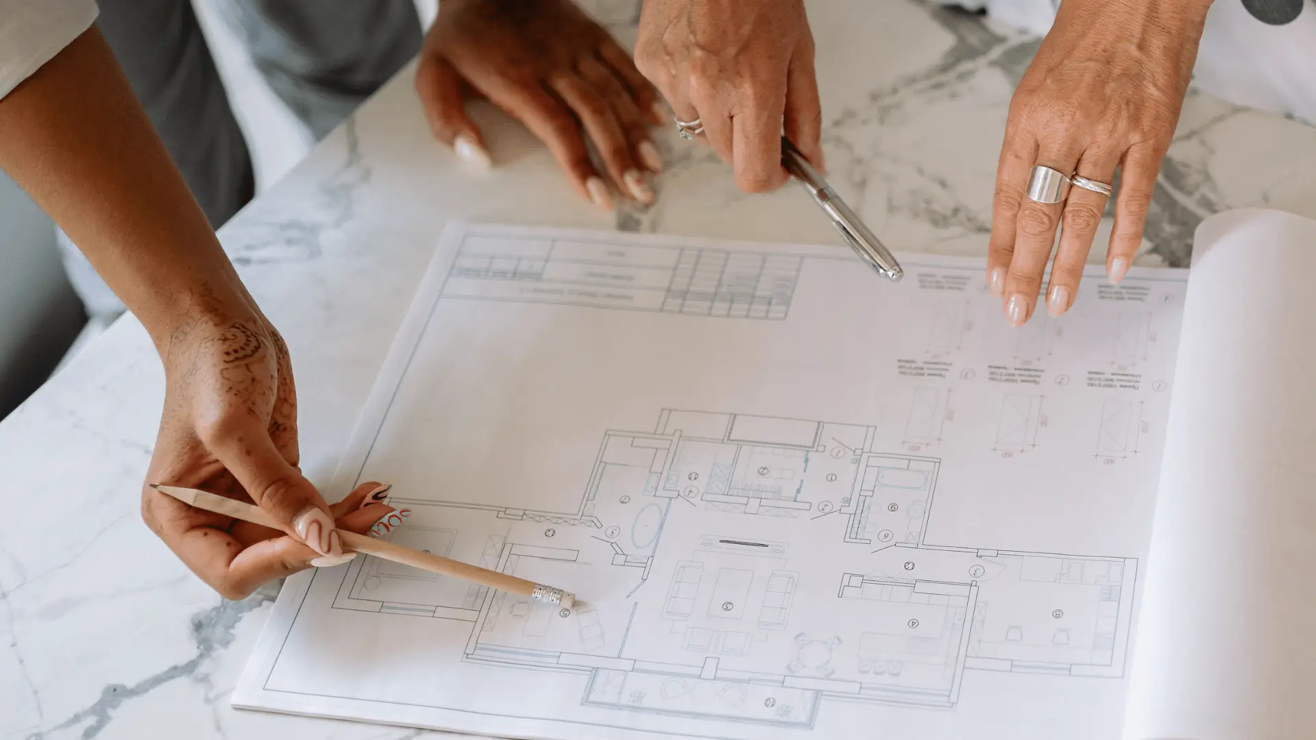 Two professionals collaborating over architectural blueprints representing financial planning strategy