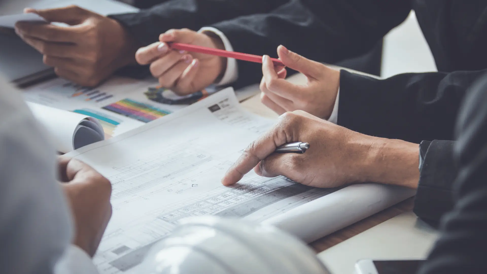 Two professionals reviewing architectural blueprints and financial bar charts as planning tools