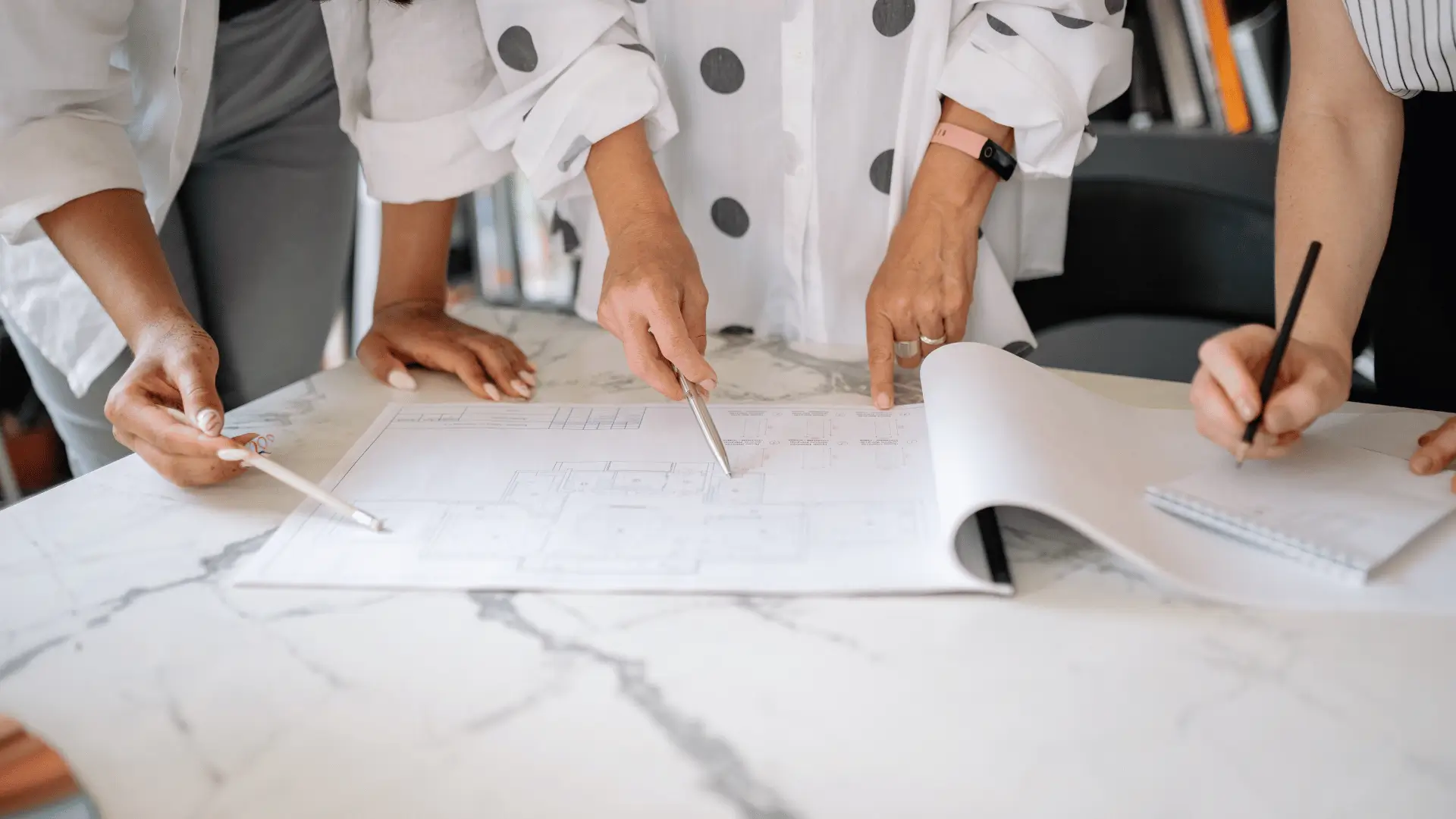 Team reviewing business entity structure and architectural plans on marble table