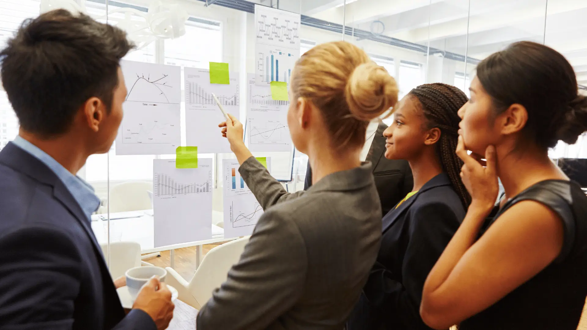 Financial team analyzing cash flow and profit planning charts on glass wall