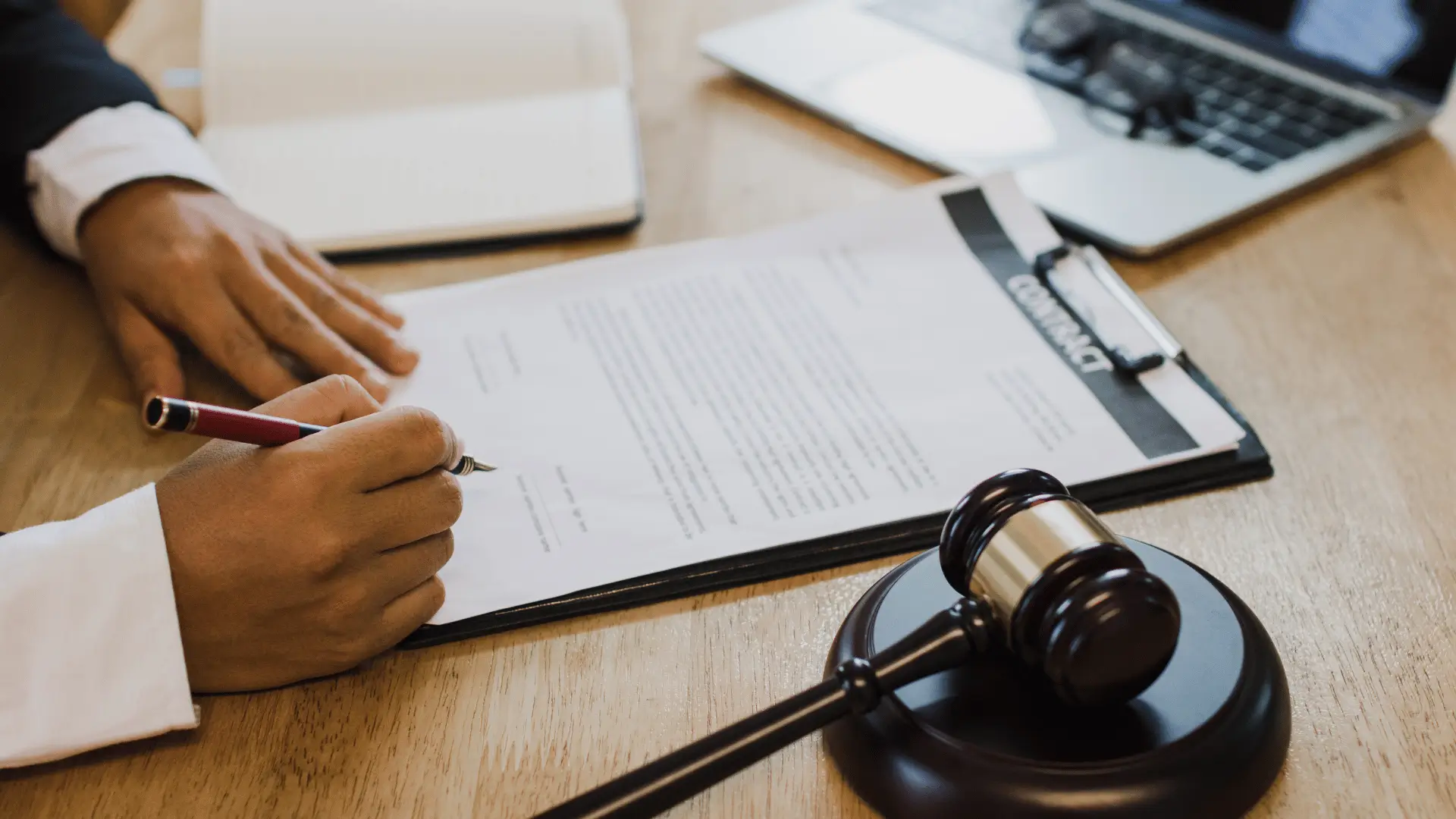 Individual signing estate planning documents at desk with legal gavel