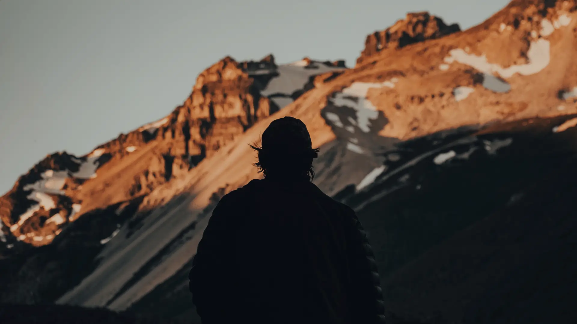 Lone figure silhouetted against rugged mountain representing the unknown risks in business planning