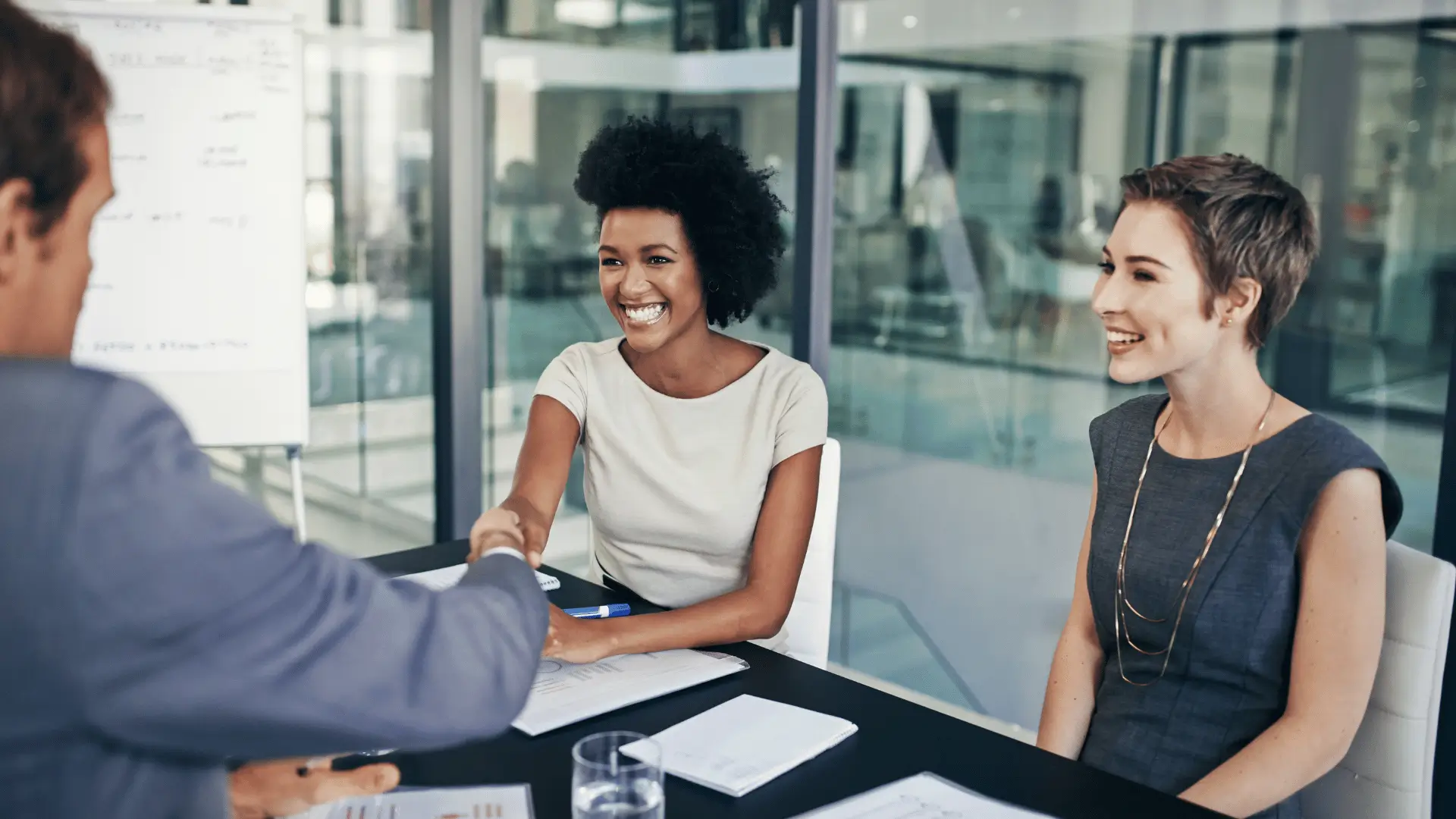 Two professional advisors completing a trusted agreement across boardroom table